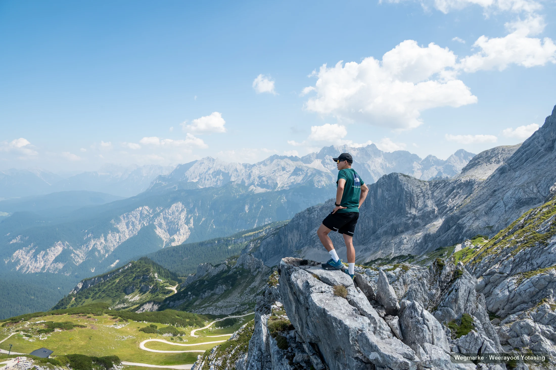 A hiker stands high above an alpine basin