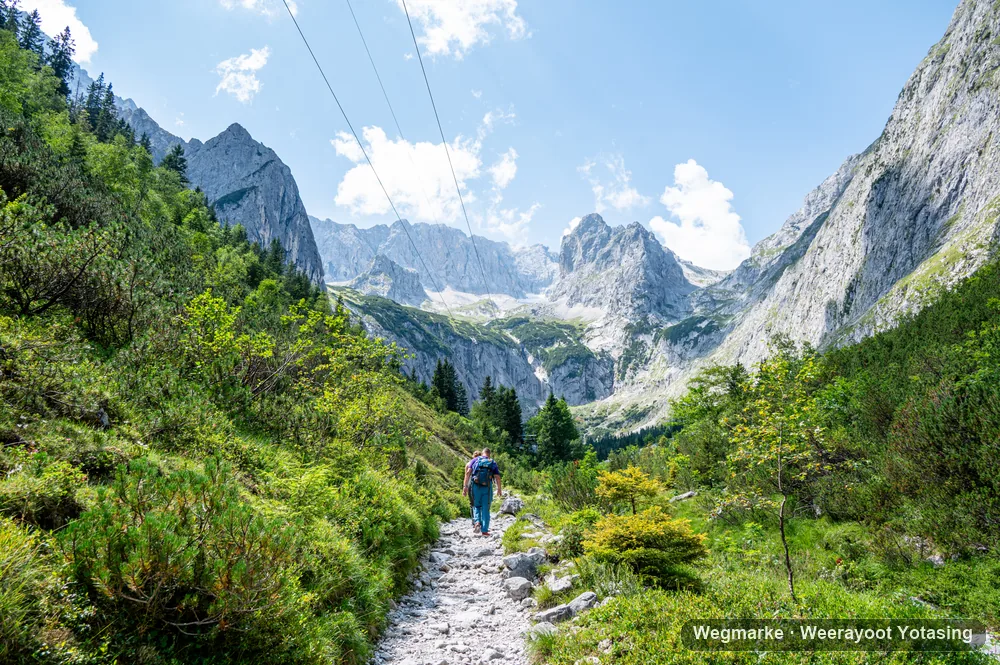 A hiker on a path leading toward high alpine peaks