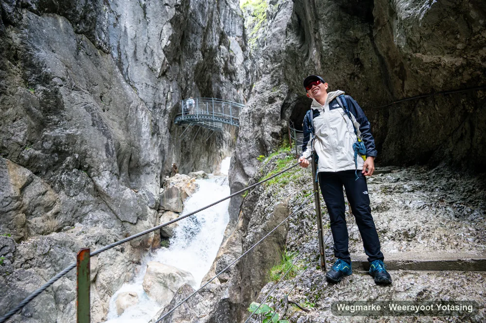 A hiker pauses on a metal stairway through a gorge